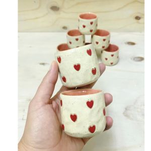 hand holding ceramic espresso cup with hearts design