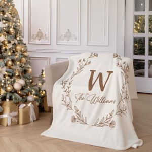 A blanket on a sofa chair it has a large initial W on it