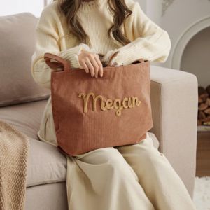 a woman holding a corduroy bag