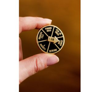 hand holding a spinner enamel pin