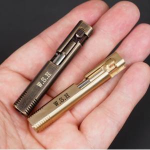 hand holding two brass pens
