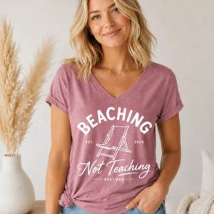 A dusty pink short sleeve V-neck tee shirt with white graphic text worn by a woman