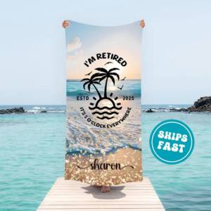 A large beach towel printed with a tropical palm tree sunset design and the name