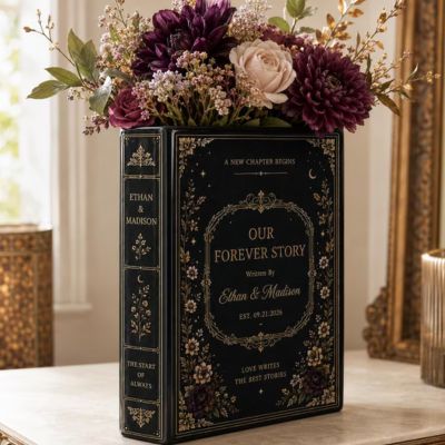 Black ceramic vase shaped like book holding purple flowers