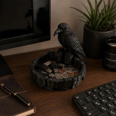 Black raven figurine perched on a round catchall tray