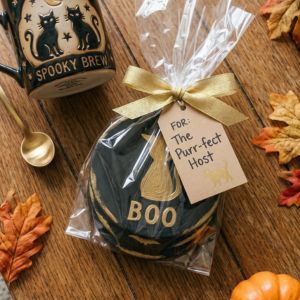 Gift-wrapped clay coasters beside a black cat mug and gift tag