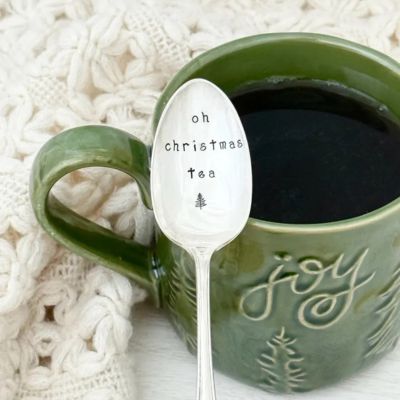 Silver spoon resting inside green mug with dark tea