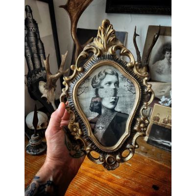 hand holding Ornate gold baroque frame with dark portrait art