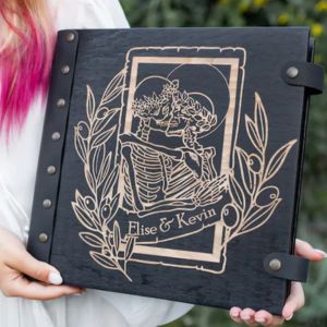 woman holding a large photoalbum with a skeleton couple on the cover